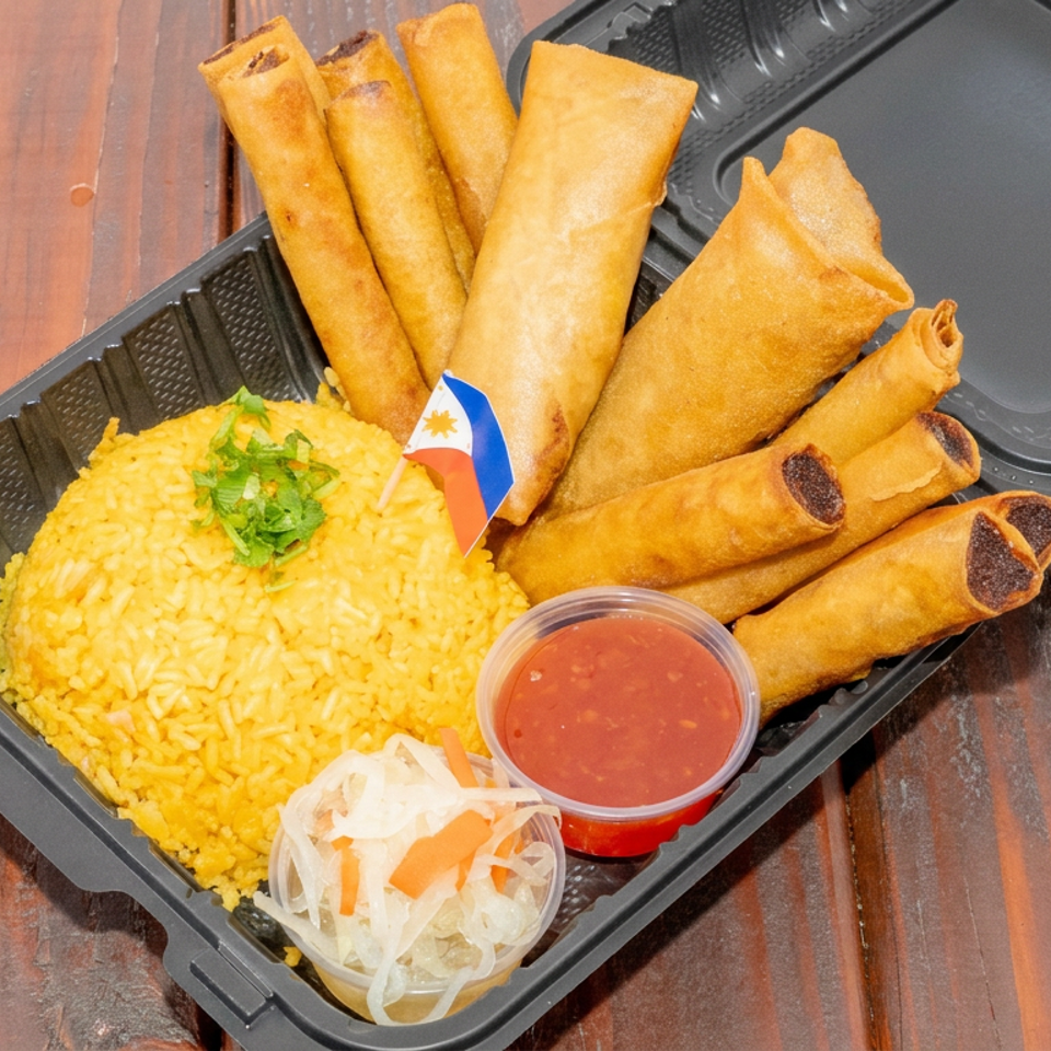 Takeout tray with yellow rice, fried spring rolls, red dipping sauce, and pickled vegetables on a wooden table.